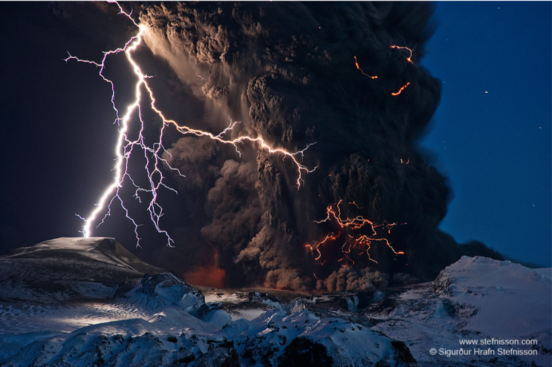 Image of lightening outside and inside dark clouds erupting out of a snow-clad volcano